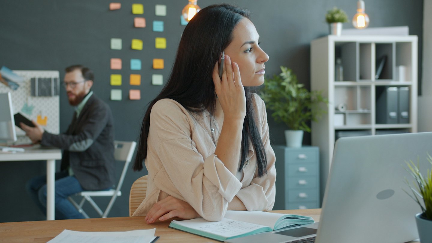Woman holding a pen while working at her desk.